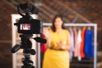 Femme vlogger caucasienne à la maison dans son dressing, démontrant des vêtements à la mode pour son blog en ligne, à l'aide d'une caméra. Distance sociale et isolement personnel en quarantaine. — Photo de stock