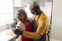 Una coppia afroamericana anziana che trascorre del tempo a casa insieme, distanziamento sociale e isolamento in quarantena durante l'epidemia di coronavirus covid 19, ballando in cucina — Foto stock