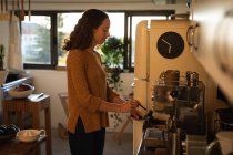 Kaukasische Frau, die während der 19-jährigen Coronavirus-Epidemie selbstisolierend und sozial distanziert in Quarantäne lebt, steht in ihrer Küche und bereitet Kaffee zu. — Stockfoto