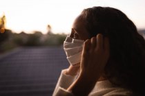 Caucasian woman spending time at home self isolating and social distancing in quarantine lockdown during coronavirus covid 19 epidemic, putting on a face mask against covid19 coronavirus, standing by a window. — Stock Photo