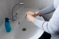 Nahaufnahme einer Frau im grauen Pullover, die sich die Hände mit Flüssigseife wäscht. Soziale Distanzierung und Selbstisolierung in Quarantäne. — Stockfoto