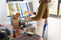 Mid section of a Caucasian woman wearing a sweater, boiling pasta for her lunch. Social distancing and self isolation in quarantine lockdown. — Stock Photo
