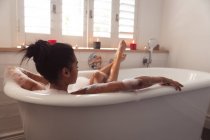 Gemischte Rassenfrau, die während der Coronavirus-Epidemie 19 in der Badewanne liegt und sich im Badezimmer entspannen kann, verbringt Zeit zu Hause mit sich selbst und sozialer Distanzierung in Quarantäne. — Stockfoto