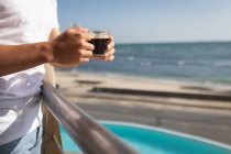Ansicht eines Mannes, der auf einem Balkon steht und eine Tasse Kaffee hält. Soziale Distanzierung und Selbstisolierung in Quarantäne. — Stockfoto
