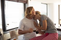 Caucasian couple standing in a kitchen, drinking coffee, embracing and talking. Social distancing and self isolation in quarantine lockdown. — Stock Photo