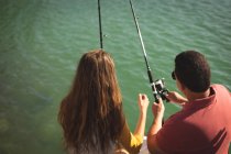Un homme caucasien et sa fille adolescente tenant des cannes à pêche et parlant — Photo de stock