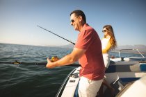 A Caucasian man and his teenage daughter holding and using fishing rods — Stock Photo