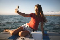 Підліток - кавказька дівчинка, яка відпочиває на сонці біля узбережжя, сидить на човні і робить свій вибір. — стокове фото