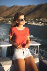 Uma adolescente caucasiana aproveitando seu tempo de férias ao sol na costa, de pé em um barco, inclinando-se, relaxando, olhando para longe — Fotografia de Stock