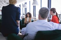 Багатоетнічна група чоловічих і жіночих колег, що працюють в сучасному офісі, зустрічаються в лаунж-зоні обговорення бізнесу та їх роботи — стокове фото
