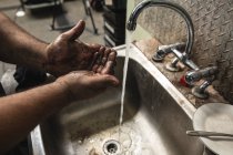 Großaufnahme eines männlichen Fabrikarbeiters, der an einer Spüle steht und sich schmutzige Hände wäscht. — Stockfoto