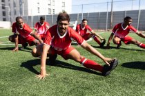 Багато етнічної команди чоловіків п'ять гравців на боці футболістів в командній стрип-тренуванні на спортивному полі на сонці, розігріваючи розтягування . — стокове фото
