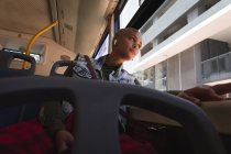 Mixed race alternative woman with short blonde hair out and about in the city, sitting on a bus wearing wireless earphones and looking out of the window. Urban digital nomad on the go. — Stock Photo