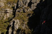 Vista lateral do homem caucasiano desfrutando de tempo na natureza, tirolesa, usando equipamento de tirolesa, em um dia ensolarado nas montanhas — Fotografia de Stock