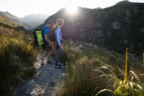 Vista laterale della coppia caucasica godendo del tempo nella natura insieme, escursioni in una giornata di sole in montagna. Divertente weekend di vacanza avventura. — Foto stock