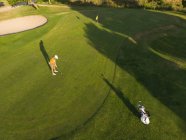 Drone tiro de um homem jogando golfe em um campo de golfe em um dia ensolarado, concentrando-se, de pé por uma bola antes de tomar um derrame — Fotografia de Stock