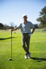 Porträt eines kaukasischen Mannes auf einem Golfplatz an einem sonnigen Tag mit blauem Himmel, der einen Golfschläger in der Hand hält und in die Kamera blickt — Stockfoto