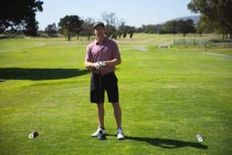 Портрет кавказького чоловіка на полі для гольфу в сонячний день з блакитним небом, з гольф-клубом, дивлячись на камеру — стокове фото