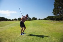 Front view of a Caucasian man at a golf course on a sunny day with blue sky, preparing to hit a golf ball — Stock Photo