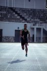Vue de face d'un athlète homme de course mixte pratiquant dans un stade de sport, sprinter vers la caméra. — Photo de stock