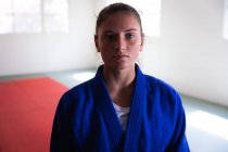 Портрет упевненої дівчини - підлітка з Кавказу, одягненої в синю дзюдоґі, що стоїть у спортзалі зі схрещеними руками і дивиться прямо в камеру.. — стокове фото