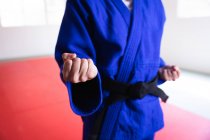 Vista frontal no meio da seção de judoca vestindo judogi azul, aquecendo antes de um treinamento em um ginásio, marcando uma pose, perfurando o ar. — Fotografia de Stock
