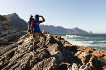 Ein fitter, behinderter Mixed-Race-Athlet mit Beinprothese, der seine Zeit bei einem Ausflug in die Berge, beim Wandern und beim Blick auf das Meer genießt. Aktiver Lebensstil mit Behinderung. — Stockfoto