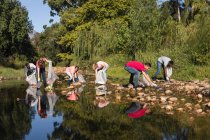 Grupo étnico multi de voluntários de conservação limpando o rio no campo, pegando lixo. Ecologia e responsabilidade social no meio rural. — Fotografia de Stock