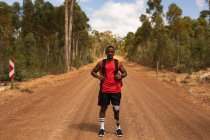 Портрет спортивного спортсмена-инвалида смешанной расы с протезной ногой, наслаждающегося путешествием, походами, стоящего на грунтовой дороге в лесу. Активный образ жизни с ограниченными возможностями. — стоковое фото