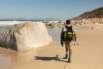 Ein fitter, behinderter Mixed-Race-Athlet mit Beinprothese, der seine Zeit bei einem Ausflug in die Berge, Wanderungen mit Stöcken und Spaziergängen am Strand am Meer genießt. Aktiver Lebensstil mit Behinderung. — Stockfoto
