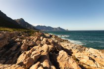 Rocky coastal cliffs by a calm, blue sea with clear blue sky on a sunny day. Beautiful natural scenery by the coast. — Stock Photo