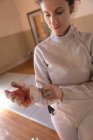 Caucasian sportswoman wearing protective fencing outfit during a fencing training session, preparing for a duel, putting glove and body cord on. Fencers — Stock Photo