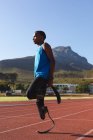 Fit, gemischt rennbehinderter männlicher Athlet in einem Outdoor-Sportstadion, der sich vor dem Training in Laufschuhen auf der Rennstrecke vorbereitet. Behindertensport. — Stockfoto
