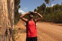 A fit, disabled mixed race male athlete with prosthetic leg, enjoying his time on a trip, hiking, standing on a dirt road in a forest, taking a break. Active lifestyle with disability. — Stock Photo