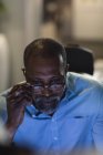 Homme d'affaires afro-américain travaillant tard le soir dans un bureau moderne, assis à un bureau, à l'aide d'un ordinateur de bureau. — Photo de stock