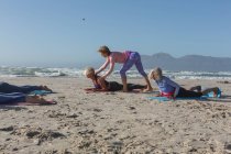 Grupo de amigas caucasianas que gostam de se exercitar em uma praia em um dia ensolarado, praticando ioga e alongamento na posição de ioga. — Fotografia de Stock