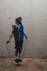 Uomo disabile di razza mista con una gamba protesica, che si allena in un parco urbano, indossa un top con cappuccio che salta con corda per saltare. Fitness disabilità stile di vita sano. — Foto stock