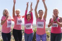Porträt einer Gruppe kaukasischer Freundinnen, die es genießen, an einem sonnigen Tag Sport zu treiben, nach dem Lauf zu feiern, Nummern zu tragen und in die Kamera zu lächeln. — Stockfoto