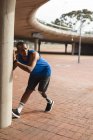 Інвалідний змішаний гоночний чоловік з протезною ногою, працює в міському парку, спираючись на стіну, розтягуючи ногу. Фітнес інвалідність здоровий спосіб життя . — стокове фото
