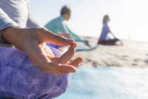 Крупный план группы кавказских подруг, наслаждающихся тренировками на пляже в солнечный день, практикующих йогу, медитирующих в позе лотоса. — стоковое фото