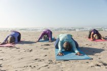 Gruppe kaukasischer Freundinnen, die an einem sonnigen Tag am Strand Sport treiben, Yoga praktizieren und in Yogaposition sitzen. — Stockfoto