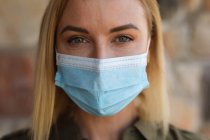 Portrait of Caucasian woman spending time at home, wearing face mask and looking at camera. Social distancing during Covid 19 Coronavirus quarantine lockdown. — Stock Photo