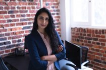 Portrait of mixed race woman working in a casual office, looking at camera. Social distancing in the workplace during Coronavirus Covid 19 pandemic. — Stock Photo