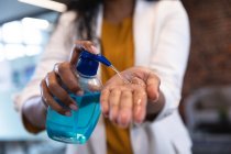 Close up of woman working in a casual office, using sanitiser. Social distancing in the workplace during Coronavirus Covid 19 pandemic. — Stock Photo