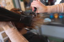Hands of female hairdresser working in hair salon, drying hair of female customer. Health and hygiene in workplace during Coronavirus Covid 19 pandemic. — Stock Photo
