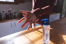 Una donna caucasica che passa del tempo a casa a disinfettare le mani in cucina. Distanza sociale durante il blocco di quarantena Covid 19 Coronavirus. — Foto stock