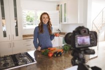Kaukasische Frau verbringt Zeit zu Hause, hackt Gemüse in der Küche und hält es mit einer Kamera fest. Soziale Distanzierung während Covid 19 Coronavirus Quarantäne Lockdown. — Stockfoto