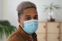 Retrato de negocio masculino de raza mixta creativo de pie en una oficina con máscara facial. Salud e higiene en el lugar de trabajo durante la pandemia de Coronavirus Covid 19. - foto de stock