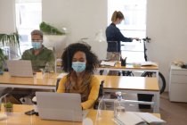 Multi ethnic group of male and female creatives working at office desks with protective screens, using laptop computers. Health and hygiene in workplace during Coronavirus Covid 19 pandemic. — Stock Photo