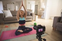 Caucasian woman spending time at home, in living room, exercising, practicing yoga and recording it with a camera. Social distancing during Covid 19 Coronavirus quarantine lockdown. — Stock Photo